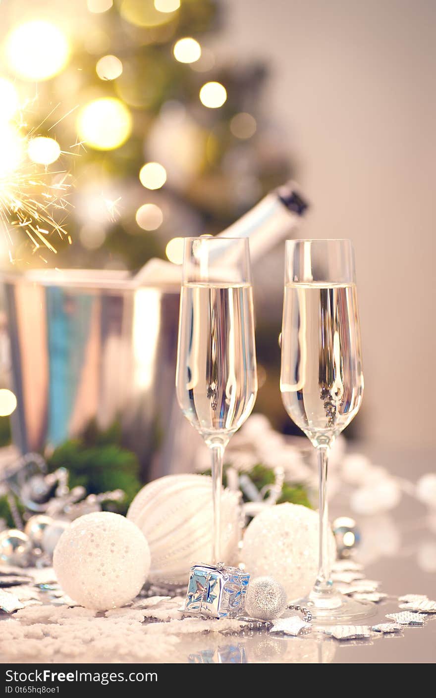 Christmas and New Year celebration with champagne. Holiday dinner table setting with Christmas tree decoration, two flutes of sparkling wine on served table, holiday Xmas dinner. Champagne