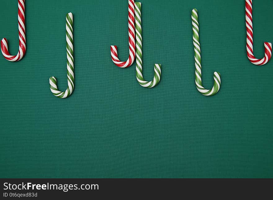 Candy sugar canes on a green background. Christmas background. Concept of Christmas and New Year. Caramel sugar cane concept Copy space. Flat lay. Pattern, card, frame.