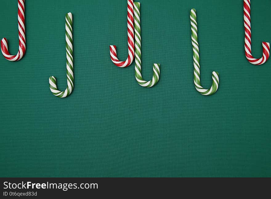 Candy sugar canes on a green background. Christmas background. Concept of Christmas and New Year. Caramel sugar cane concept Copy