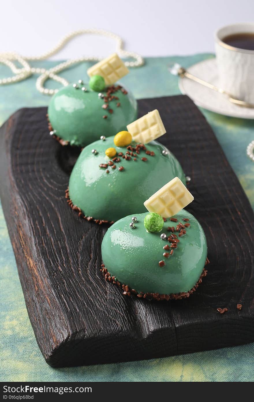 Homemade bright mousse cakes Hearts with green mirror icing, Closeup, vertical orientation