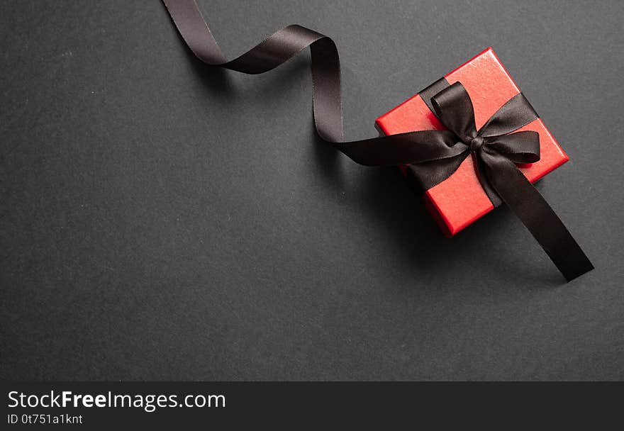 Gift box with black ribbon against black background, Black Friday concept