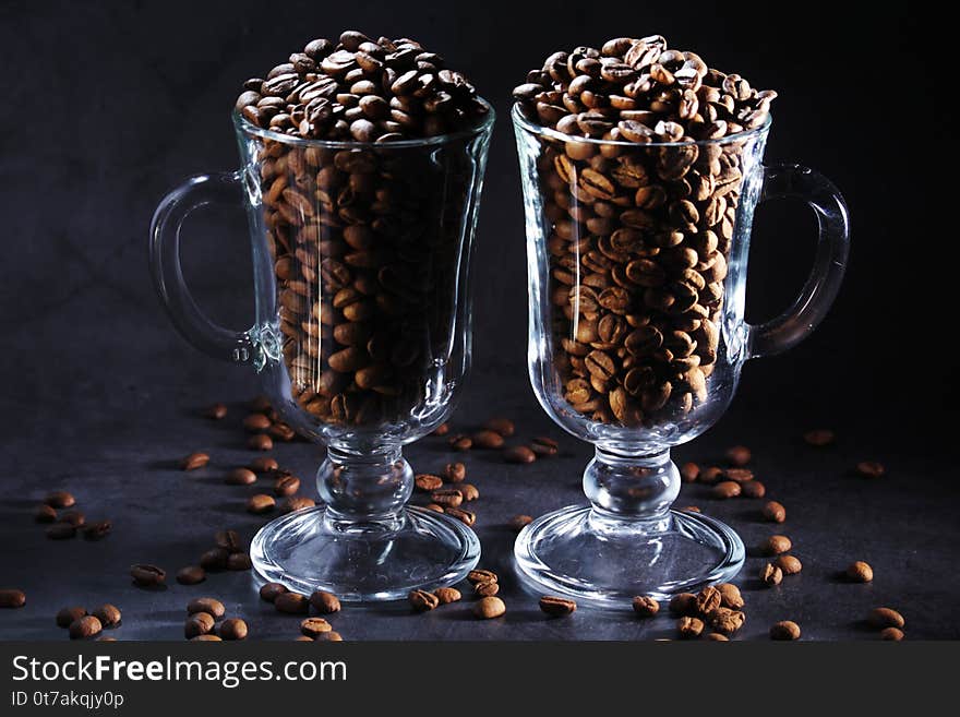 Two glasses full of coffee beans with cinnamon agaist dark background as a concept of coffee drinking. Two glasses full of coffee beans with cinnamon agaist dark background as a concept of coffee drinking