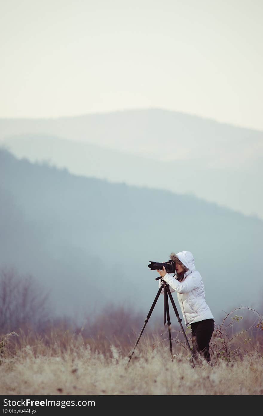 photographer with camera and tripod outdoor taking landscape picture