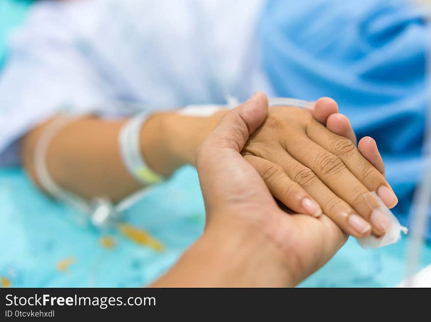 Husband holding wife hand giving normal saline solution or sodium chloride after surgery in hospital