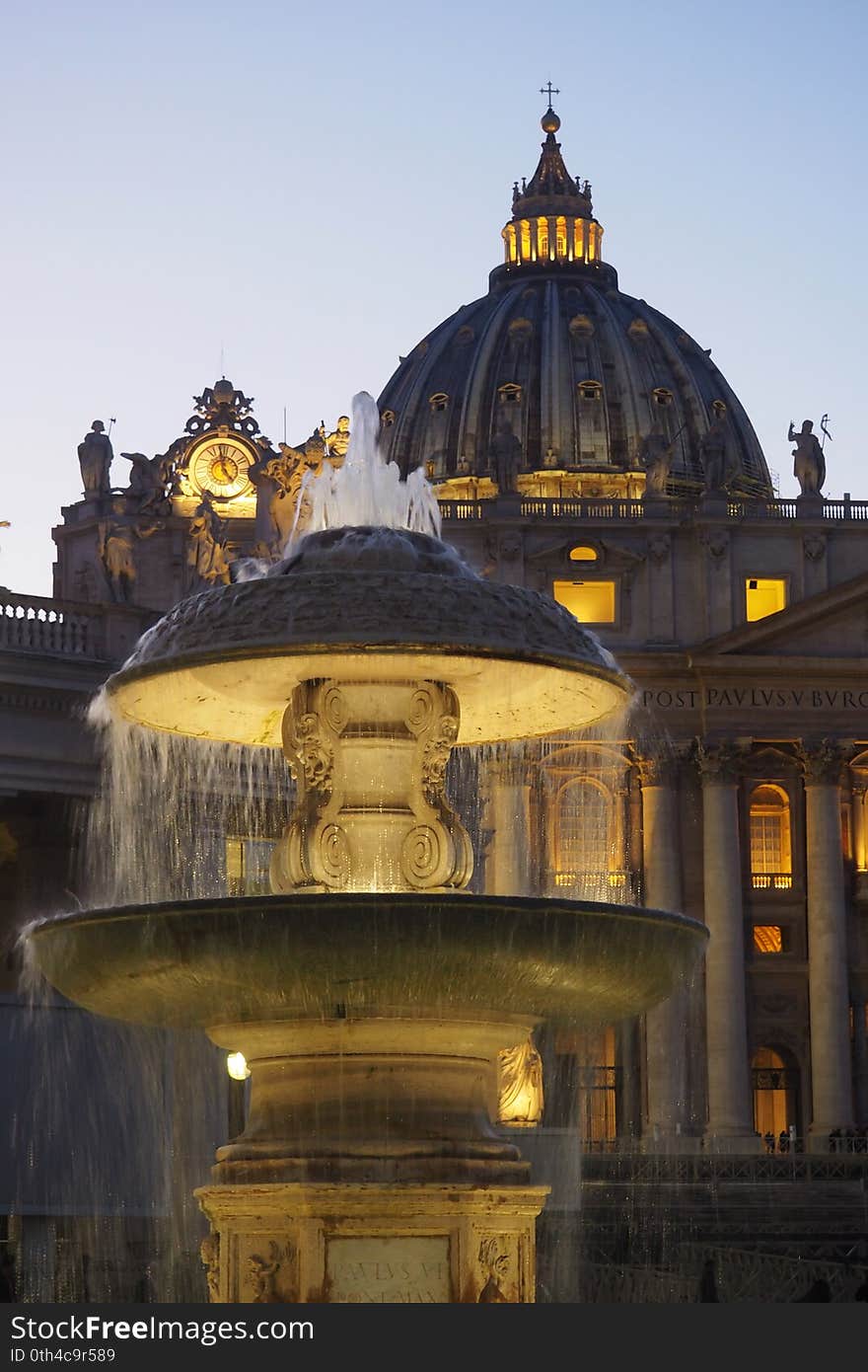 View of the St. Peter`s Basilica from the granite fountain  in the Vatican City, Rome, Italy. The open space which lies before the basilica was redesigned by Gian Lorenzo Bernini from 1656 to 1667, under the direction of Pope Alexander VII. Bernini created a perfect alignment among Maderno`s baroque facade and the oval square surrounded by the massive Doric colonnades,four columns deep, which embrace visitors in `the maternal arms of Mother Church`. The granite fountain was constructed by Bernini in 1675 and matches another fountain designed by Carlo Maderno in 1613. View of the St. Peter`s Basilica from the granite fountain  in the Vatican City, Rome, Italy. The open space which lies before the basilica was redesigned by Gian Lorenzo Bernini from 1656 to 1667, under the direction of Pope Alexander VII. Bernini created a perfect alignment among Maderno`s baroque facade and the oval square surrounded by the massive Doric colonnades,four columns deep, which embrace visitors in `the maternal arms of Mother Church`. The granite fountain was constructed by Bernini in 1675 and matches another fountain designed by Carlo Maderno in 1613.