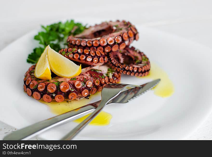 Delicious octopus salad with dressing, lemon and parsley on white background. Healthy eating. Seafood cooking