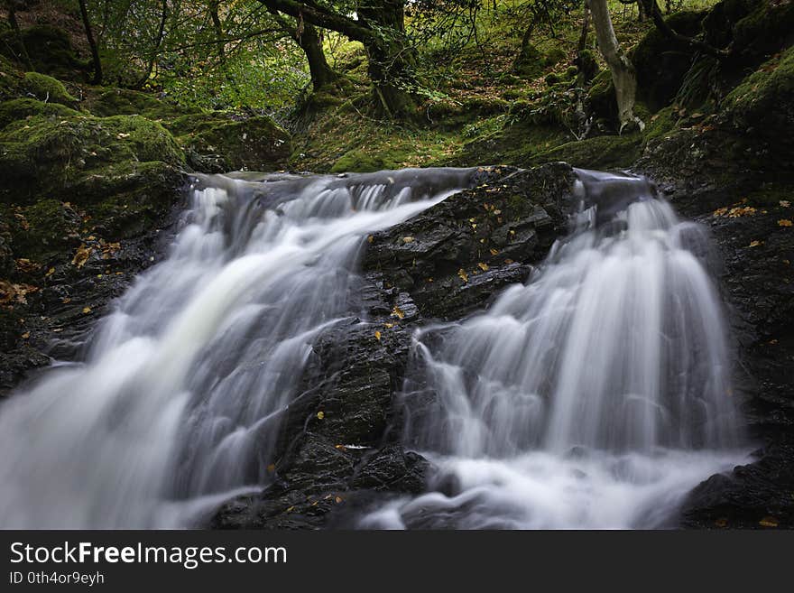 Tranquil autumn woodland scene with waterfall in Scottish highlands