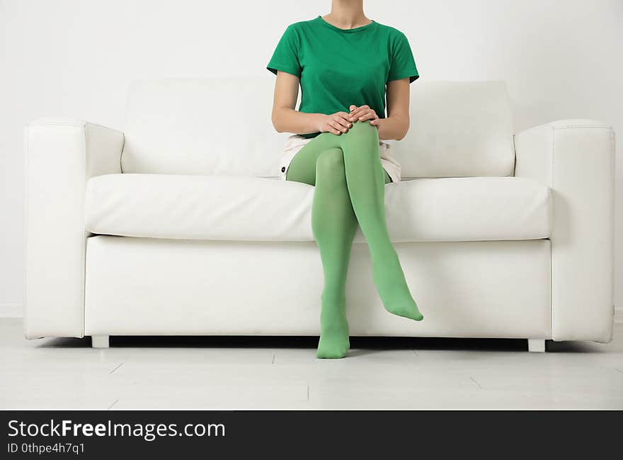 Woman wearing green tights sitting on sofa, closeup