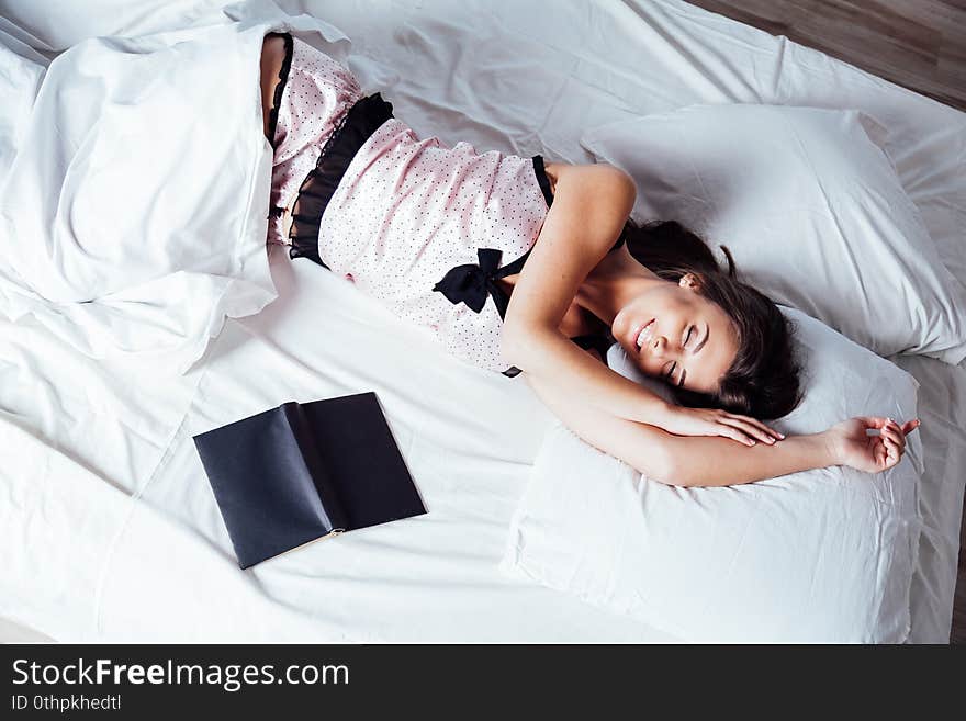 Girl in pajamas lying on the bed with a book before bed