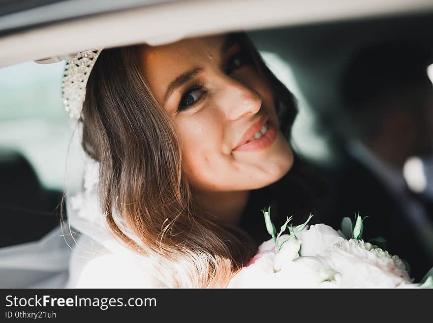 Beautiful bride sitting in the luxury retro car on wedding day