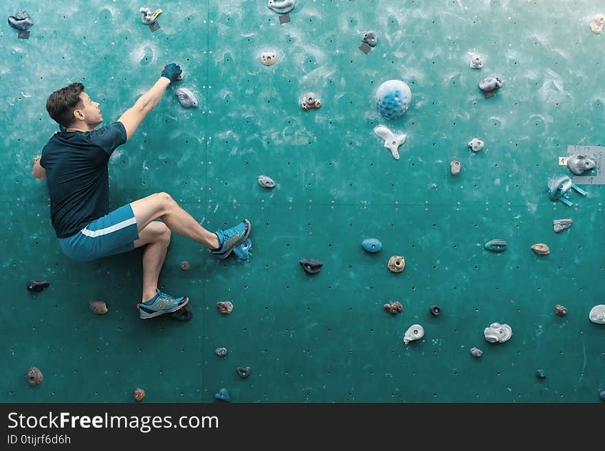 A man climbing in boulder gym in the wall.