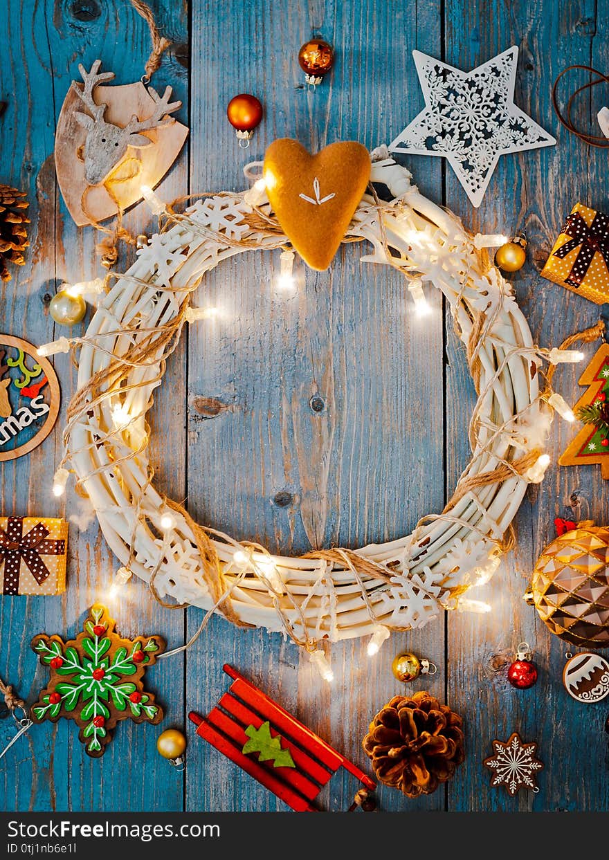 New year decorations around Christmas wreath burning lights garlands on blue wooden background. View from above. Flat lay. copy space. New year decorations around Christmas wreath burning lights garlands on blue wooden background. View from above. Flat lay. copy space