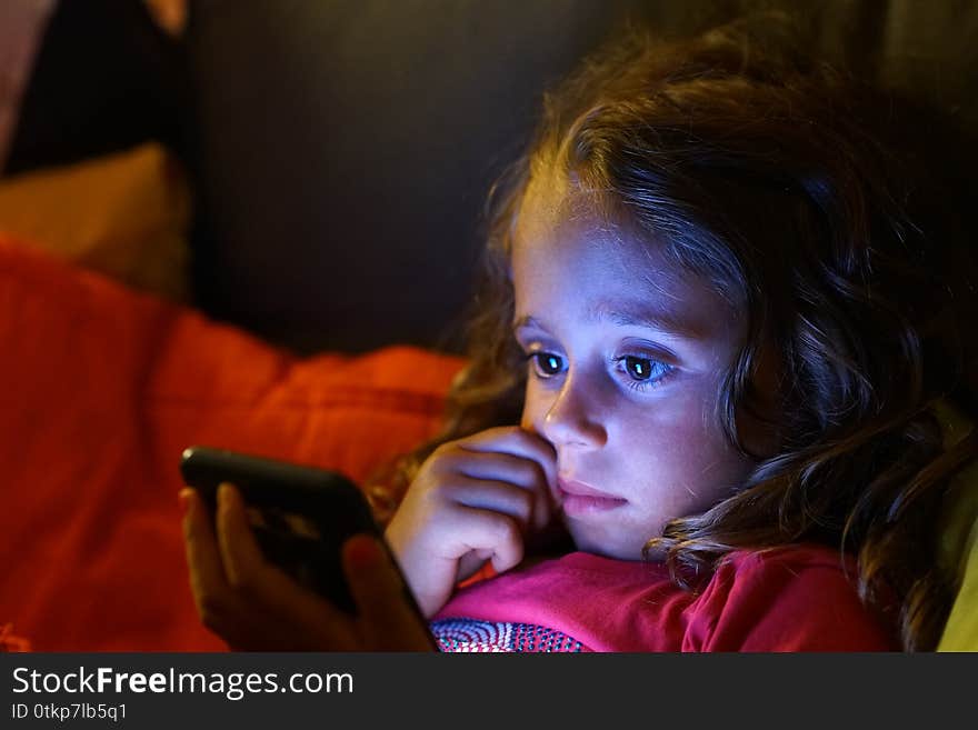 4 Year Old Girl Looks With Interest At Her Cell Phone