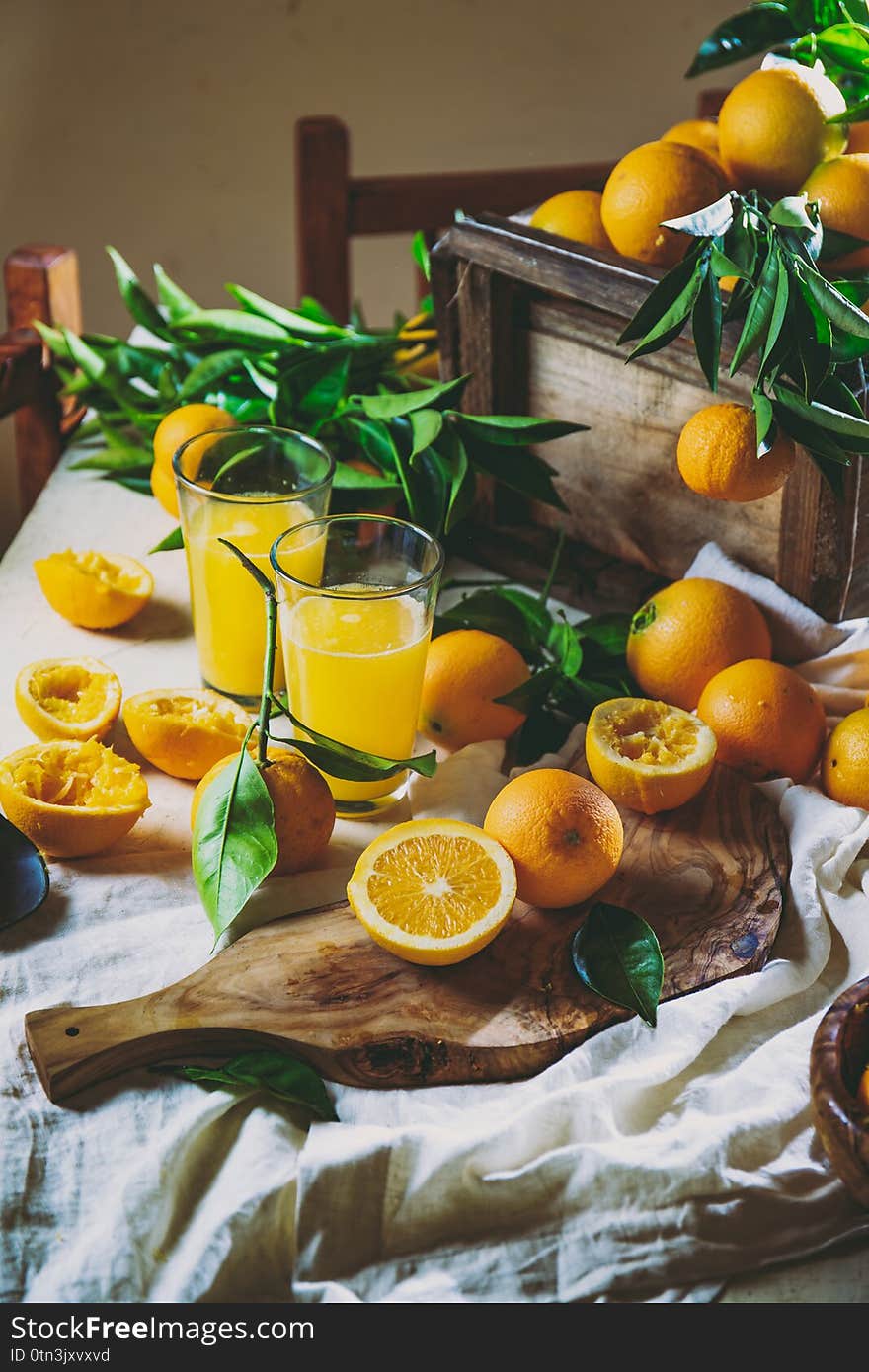 Table with box of fresh orange with orange tree branch and fresh orange juice.