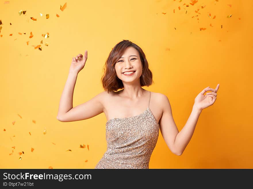 Young woman dancing under confetti at home, celebrating birthday