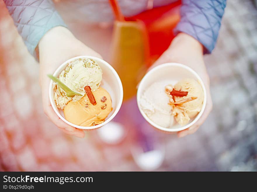 Female hands holding colored ice cream. Top view. Light toned photo, soft focus