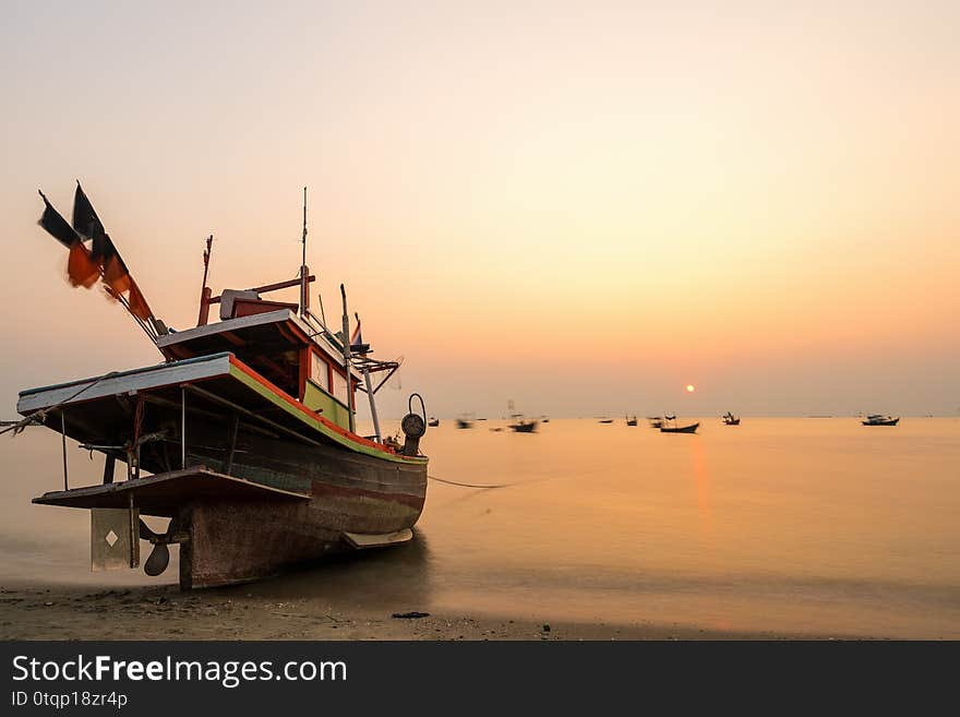 Beautiful seascape sunset with golden sunshine and fishing boat at the beach with copy space long exposure