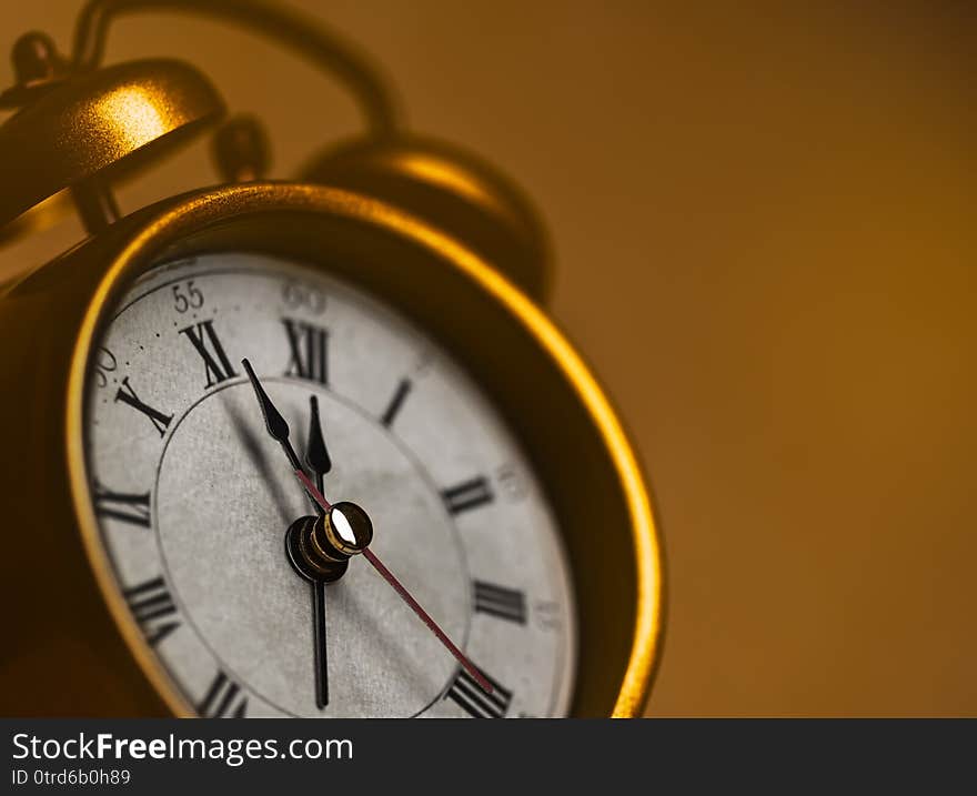 Vintage alarm clock showing five to twelve on the wooden table. Vintage alarm clock showing five to twelve on the wooden table