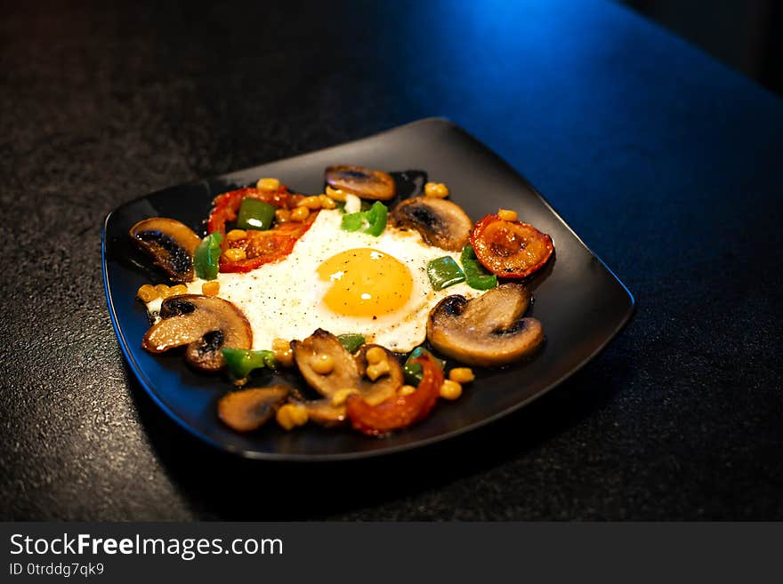 Freshly fried scrambled eggs with vegetables on a black plate