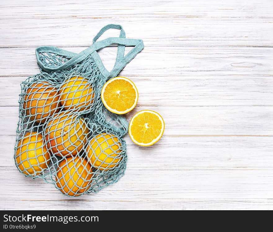 Mesh shopping bag with organic  oranges on white wooden background. Flat lay, top view. Zero waste, plastic free concept. Healthy clean eating diet and detox. Summer fruits. Mesh shopping bag with organic  oranges on white wooden background. Flat lay, top view. Zero waste, plastic free concept. Healthy clean eating diet and detox. Summer fruits