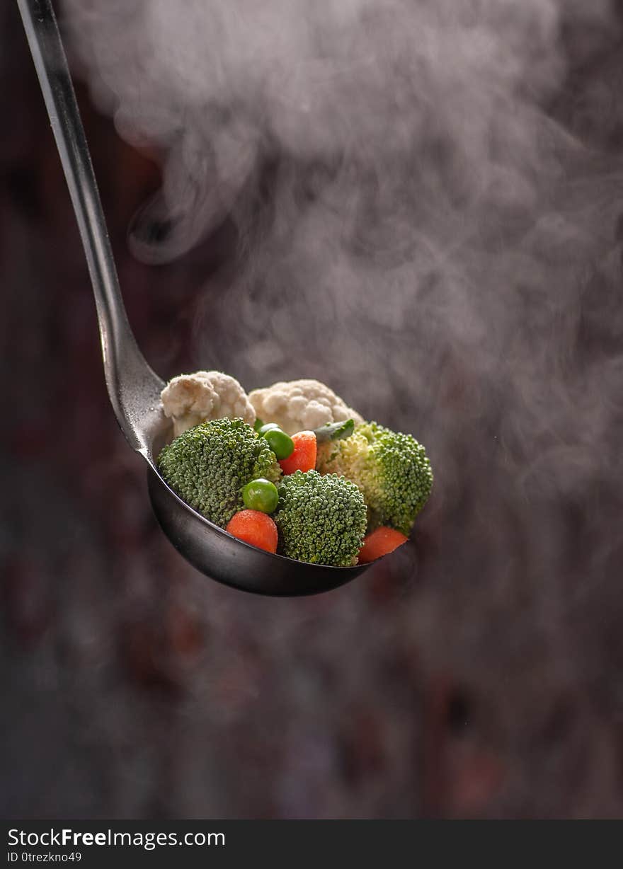 Still life with a big spoon and vegetables on it with steam