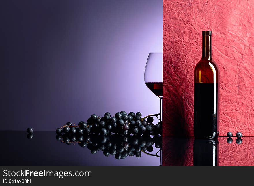 Bottle and glass of red wine on a black table. Free space for your text. Focus on foreground