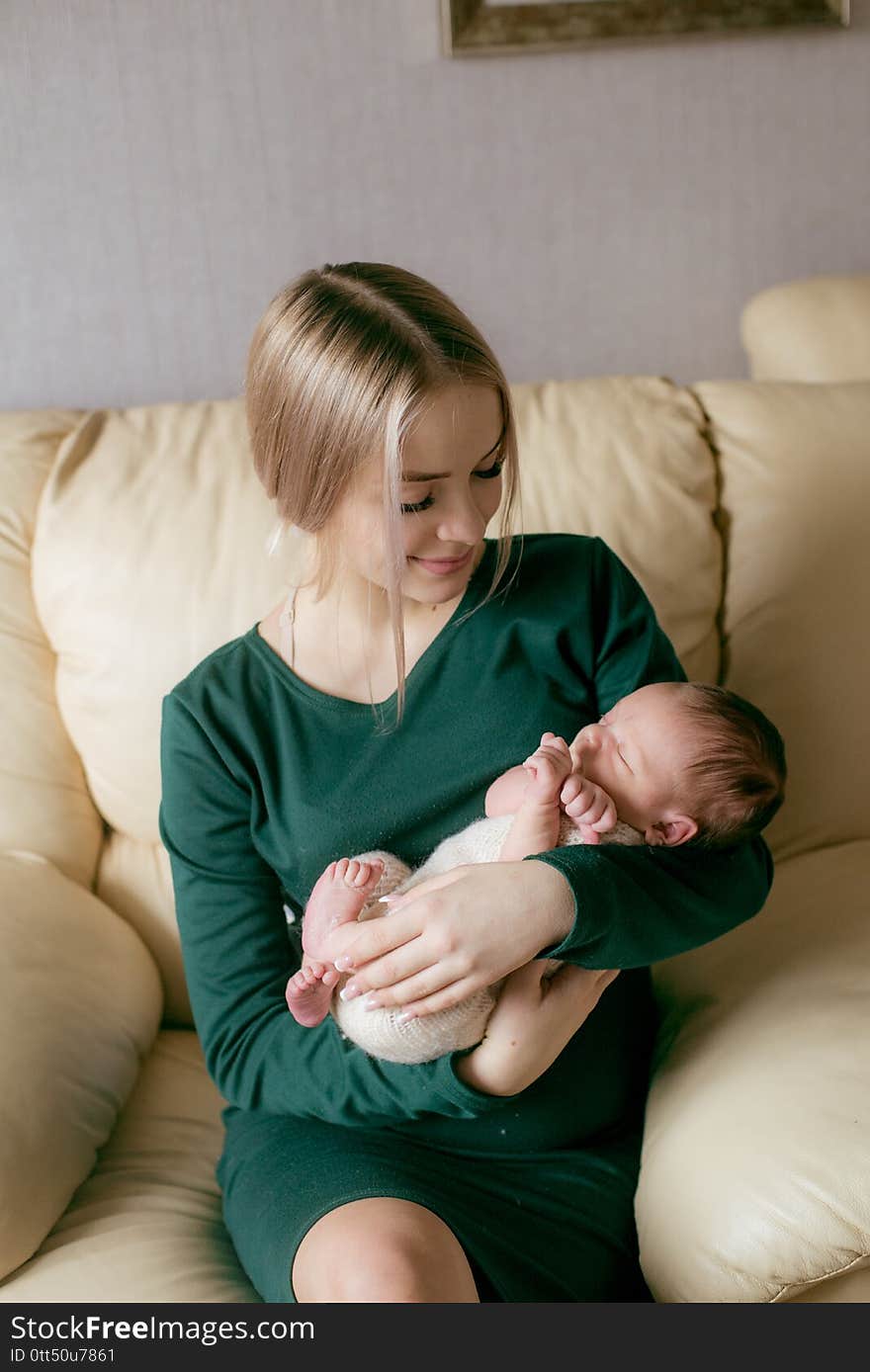 Young beautiful blond hair mamaso with a baby in her arms at home. Happy motherhood