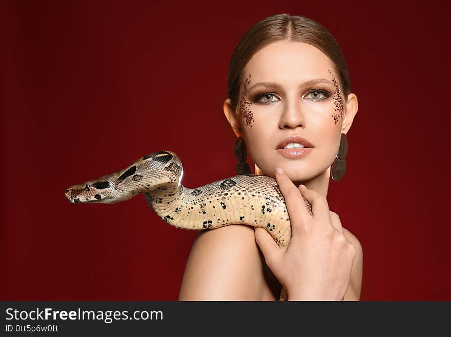 Beautiful woman with boa constrictor on bright colorful  background