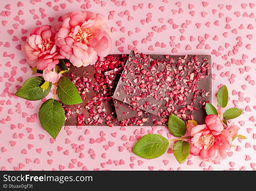 Chocolate with Pieces of Dried Strawberries Lies Stack on Pink Table with Flower