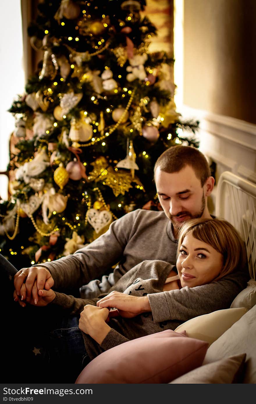 Loving young couple spends Christmas at home near a decorated, festive Christmas tree. Man and woman are happy spending