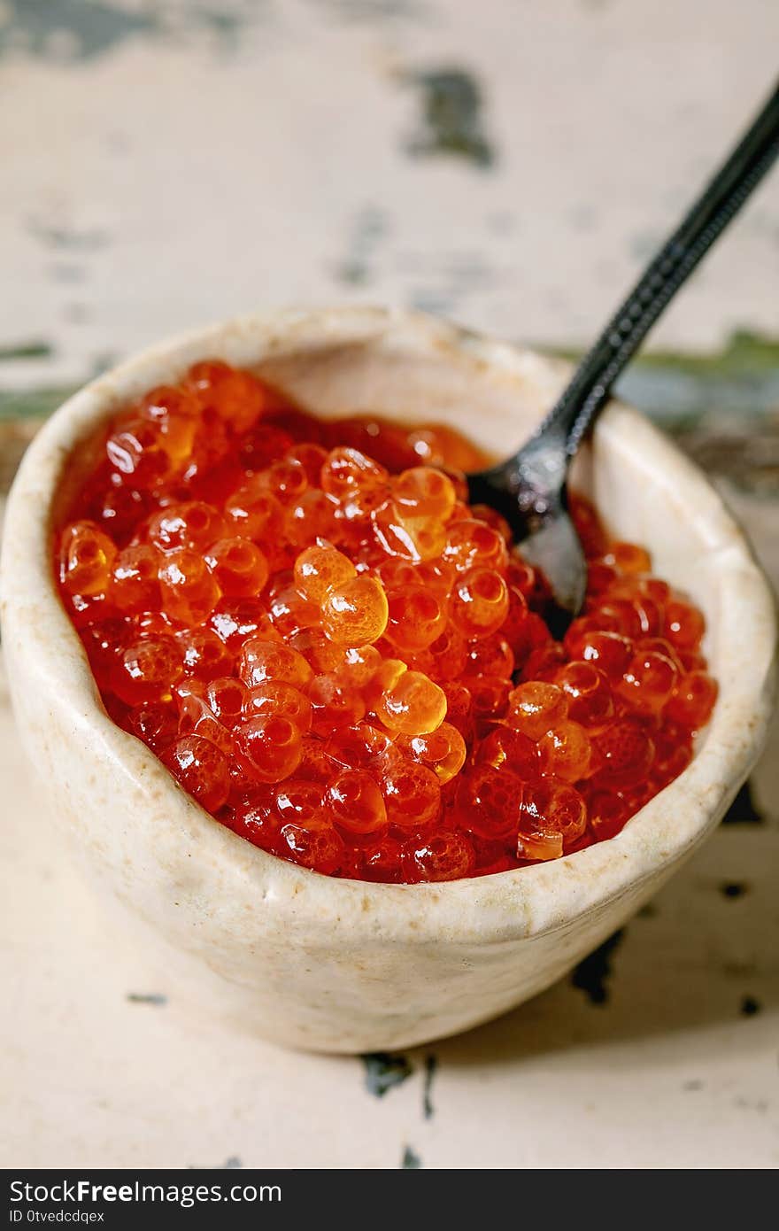 Red salmon caviar in ceramic bowl with spoon on old wooden table. Rustic style, close up. Red salmon caviar in ceramic bowl with spoon on old wooden table. Rustic style, close up