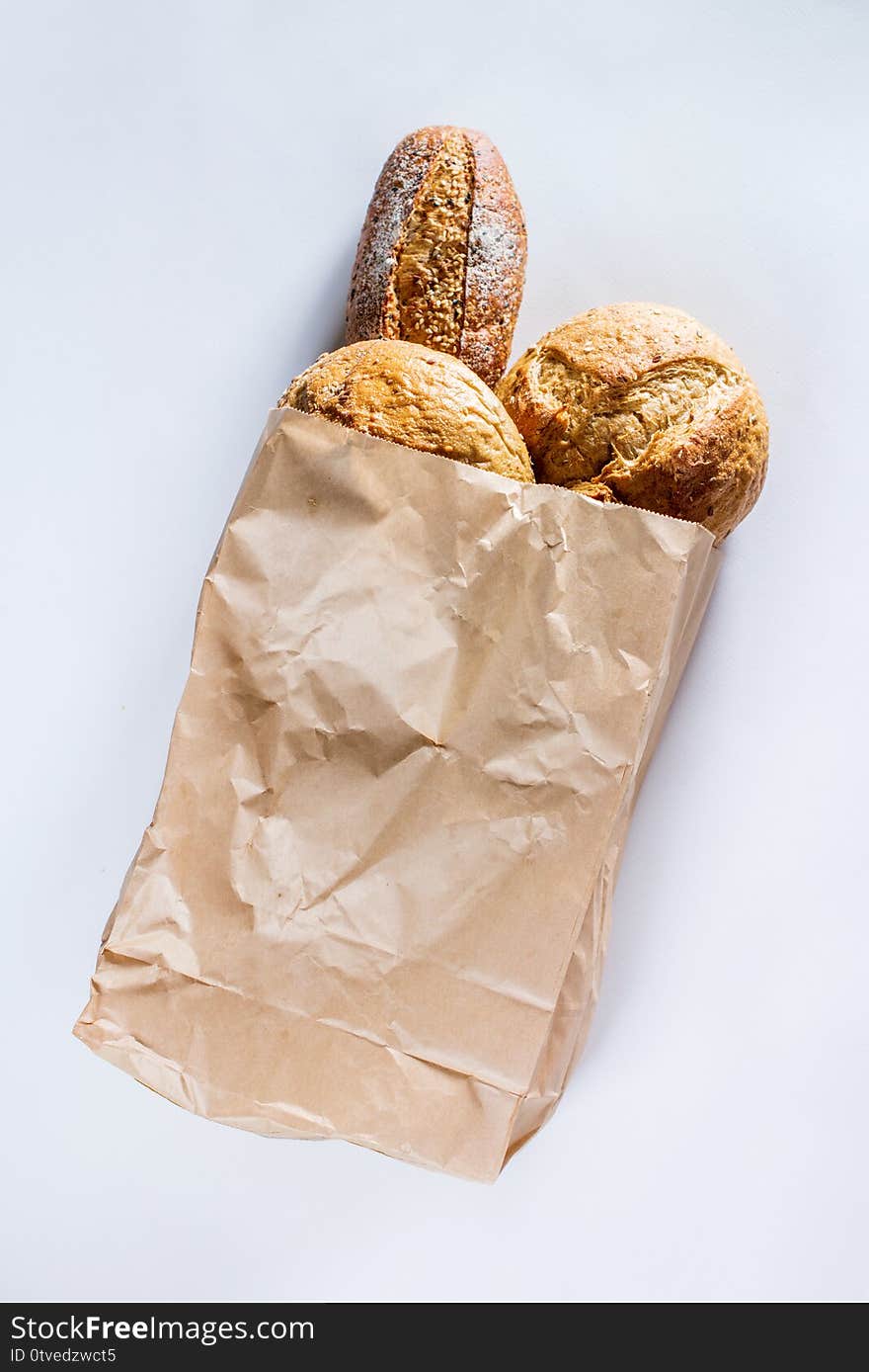 Whole grain bread with seeds in ecology paper bag on light gray background. Top view flat lay. Healthy food. Save ecology concept. Zero waste recycling