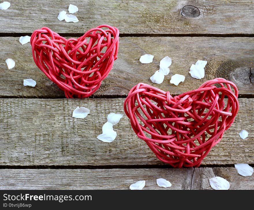 Love hearts with blossom petals on wooden plank background with space for text