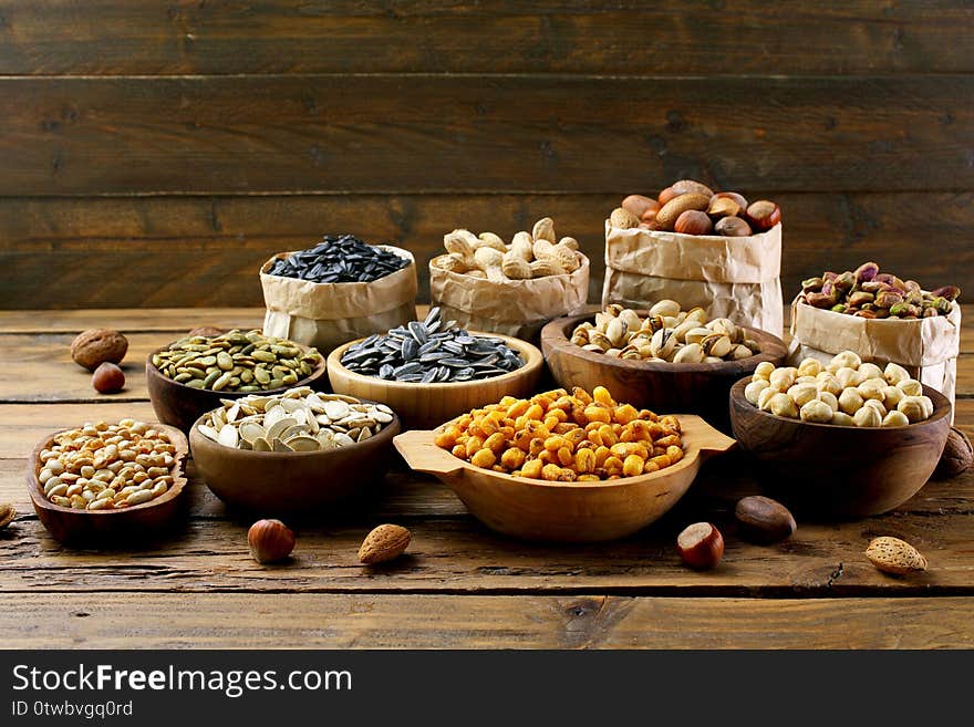 Salted seeds and nuts assortment on wooden table background. Salted seeds and nuts assortment on wooden table background