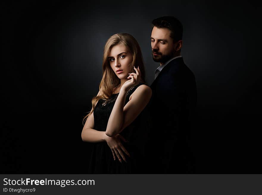 Elegant couple on black background. handsome men and beautiful women in black dress