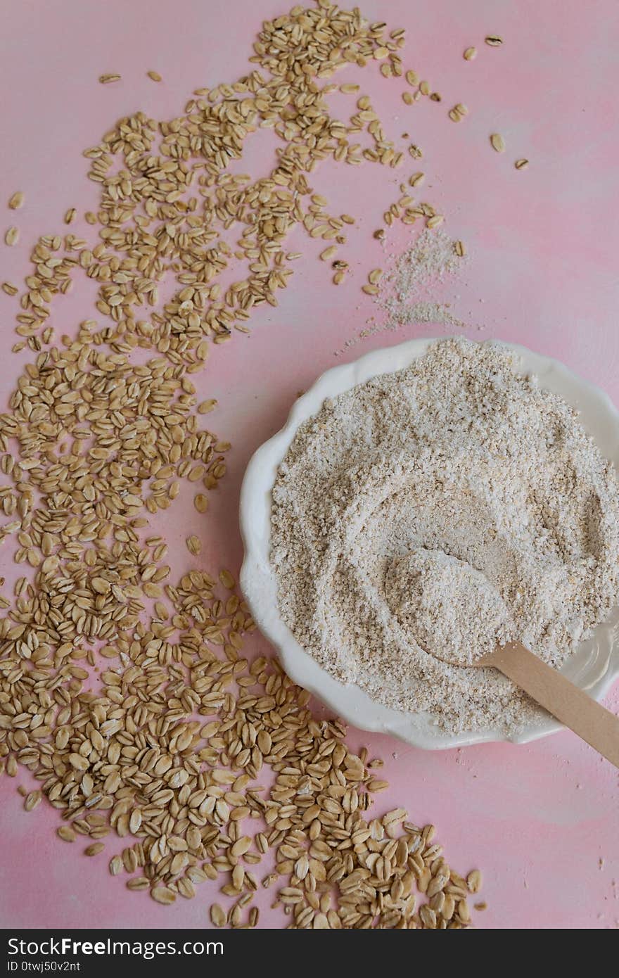 Oat food ingredients - flour and flakes on pink background