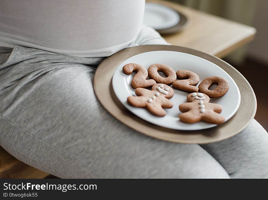 Cropped photo of pregnant woman holding number 2020 of ginger cookies on belly