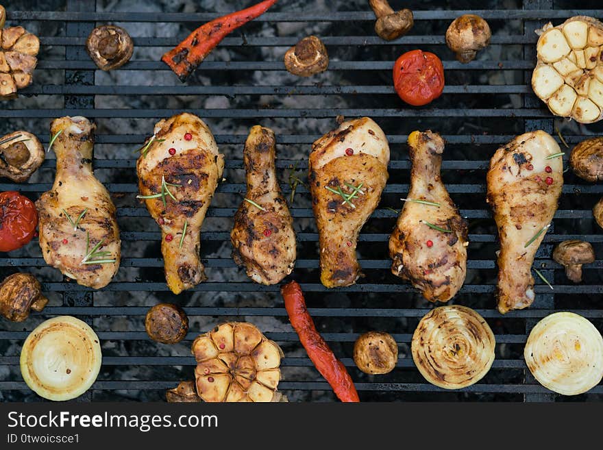 Closeup of a barbecue grill with chicken legs and vegetables