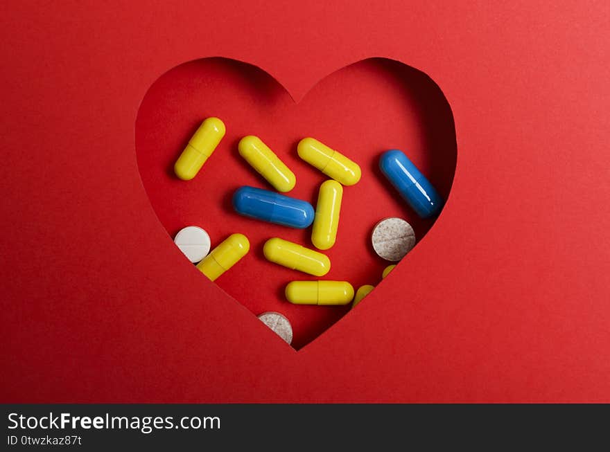 Top view of red  heart shape and pills.Concept of healthy heart and prevention of disease.Empty space for text Top view of heart shape, vitamin, drugs. Concept of heart disease and medical treatments