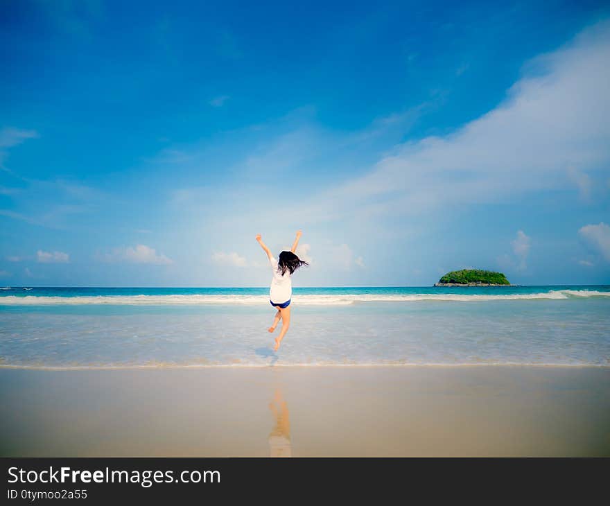 The woman was jumping on the beach with blue sky and island background. The woman was jumping on the beach with blue sky and island background