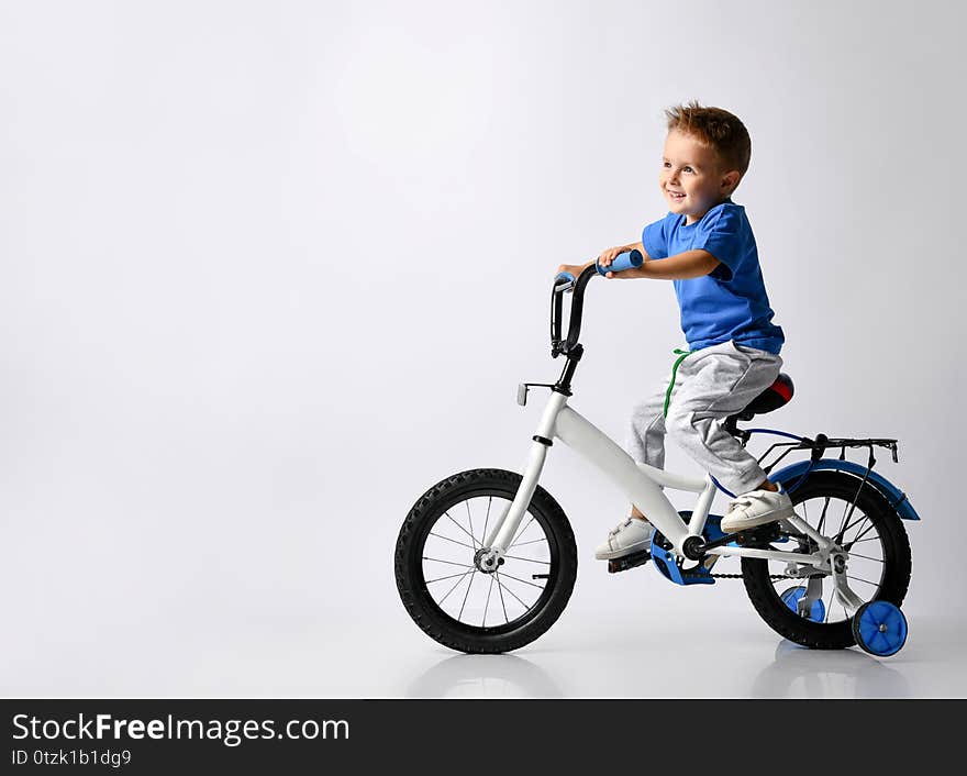 Young boy with curly brown hair happily riding on a bicycle on  background. Young boy with curly brown hair happily riding on a bicycle on  background