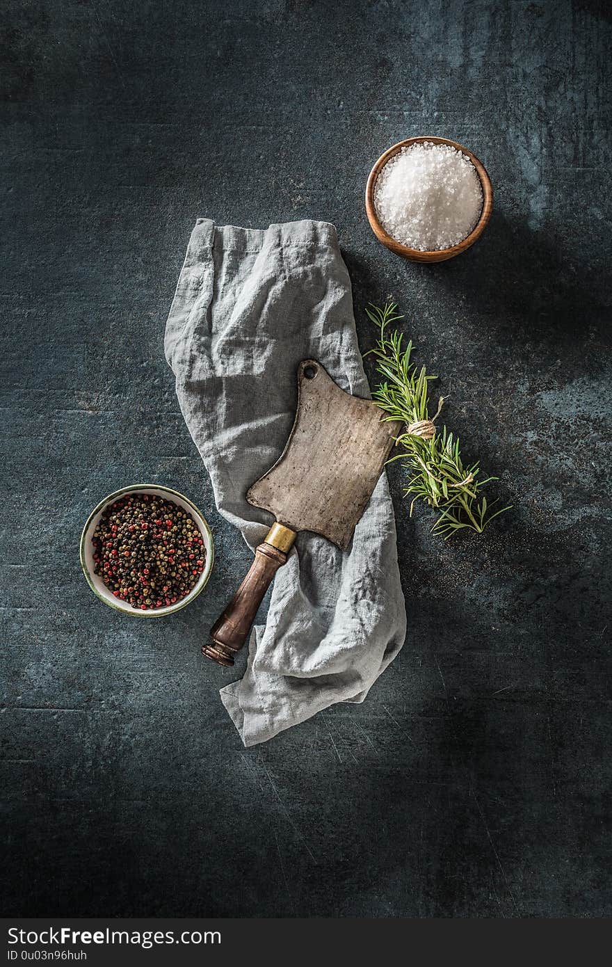 Old meat butcher on dark concrete board with herbs salt and pepper.