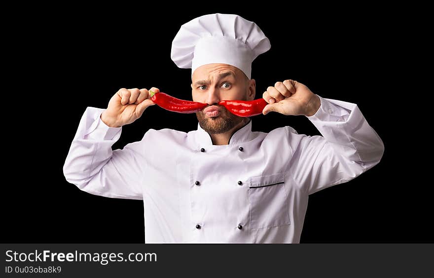 Funny Chef Man Holding Two Red Peppers Near Face Like Moustaches Having Fun Cooking Food Standing Over Black Background. Panorama. Funny Chef Man Holding Two Red Peppers Near Face Like Moustaches Having Fun Cooking Food Standing Over Black Background. Panorama