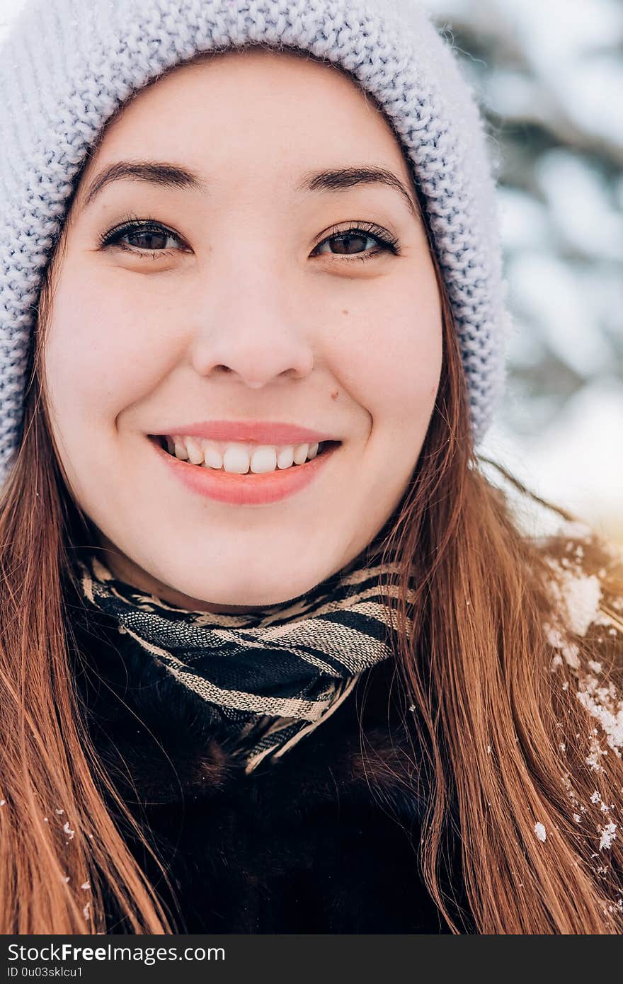 Close-up winter portrait of a beautiful smiling woman and looking at the camera. Human positive emotions concepts. Close-up winter portrait of a beautiful smiling woman and looking at the camera. Human positive emotions concepts