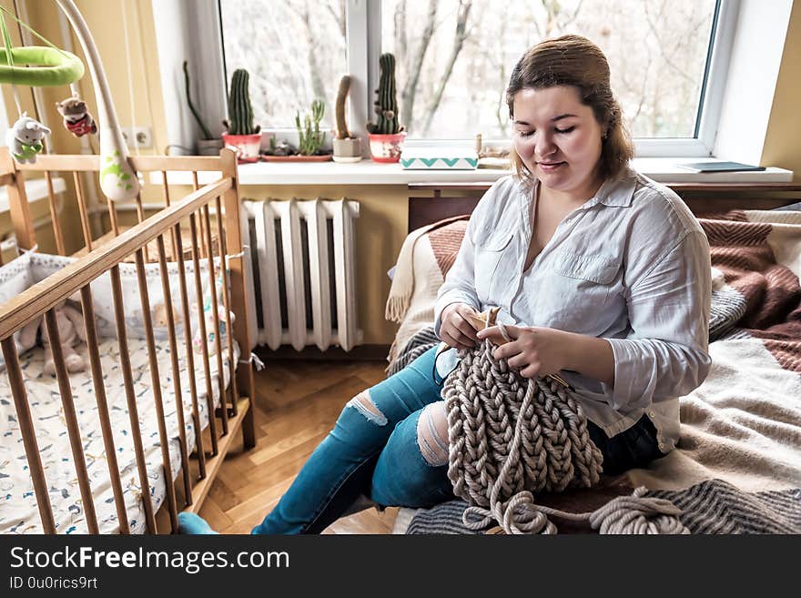 Young happy fat woman knits the scarf. Young happy fat woman knits the scarf