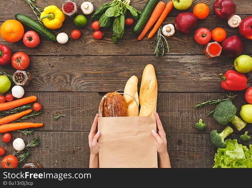 Woman hands with bread near raw organic vegetables on table