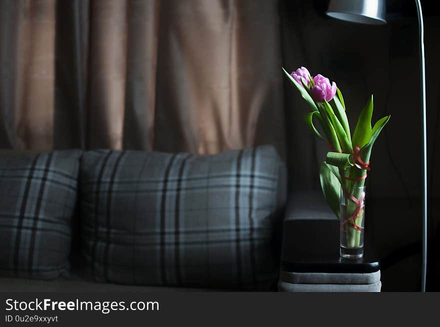 Flowers tulips in the vase in minimalism interior flat. Darkness style