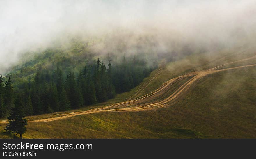 Clouds covered the tops of mountains, a dirt road in the mountains_