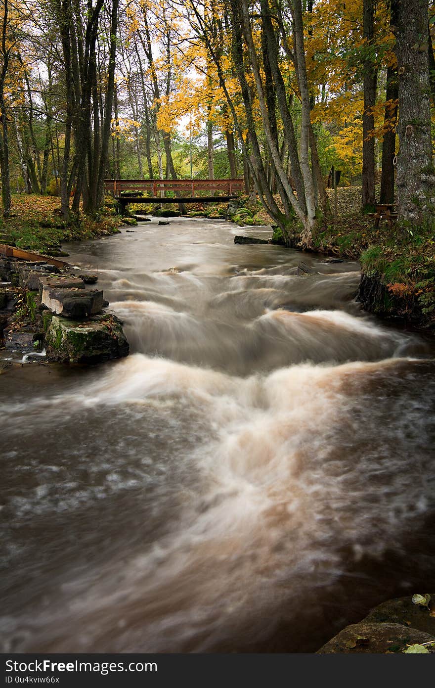 A bridge over the river in autumn colors. Streaming water. A bridge over the river in autumn colors. Streaming water.