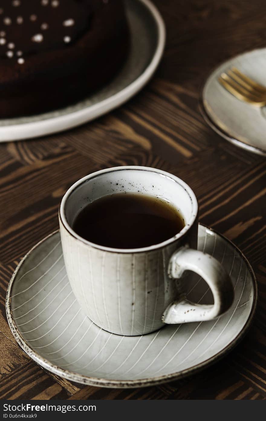 Moist Ginger Chocolate cake sprinkled with sea salt and cup of tea on wooden table. Selective focus